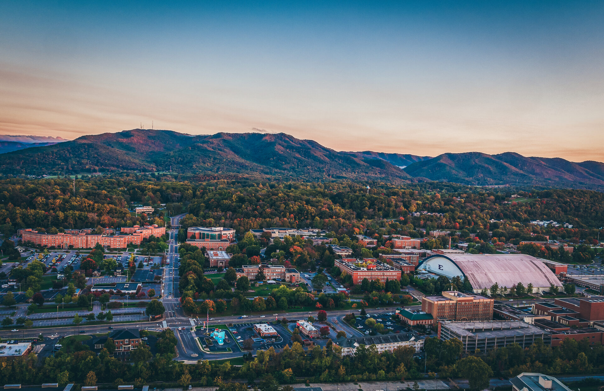 Aerial view of the ETSU campus in Johnson City at sunset, with the Blue Ridge Mountains in the background