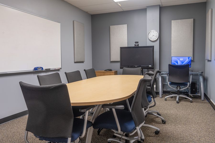 A small conference room with a wall display, video-conference ready