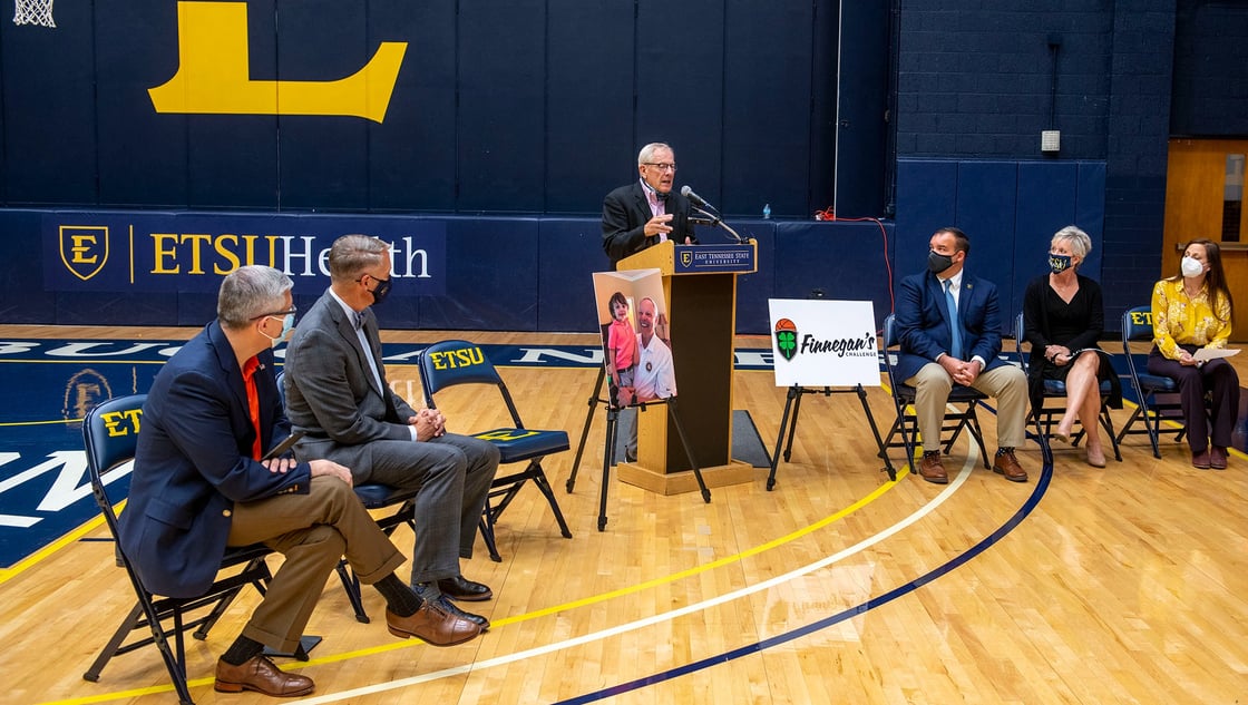 Doc stands at a podium in Brooks Gym during a press conference. 