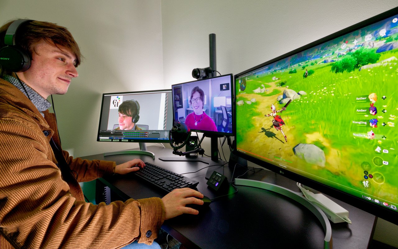 Young man looking at three computer monitors while gaming. 
