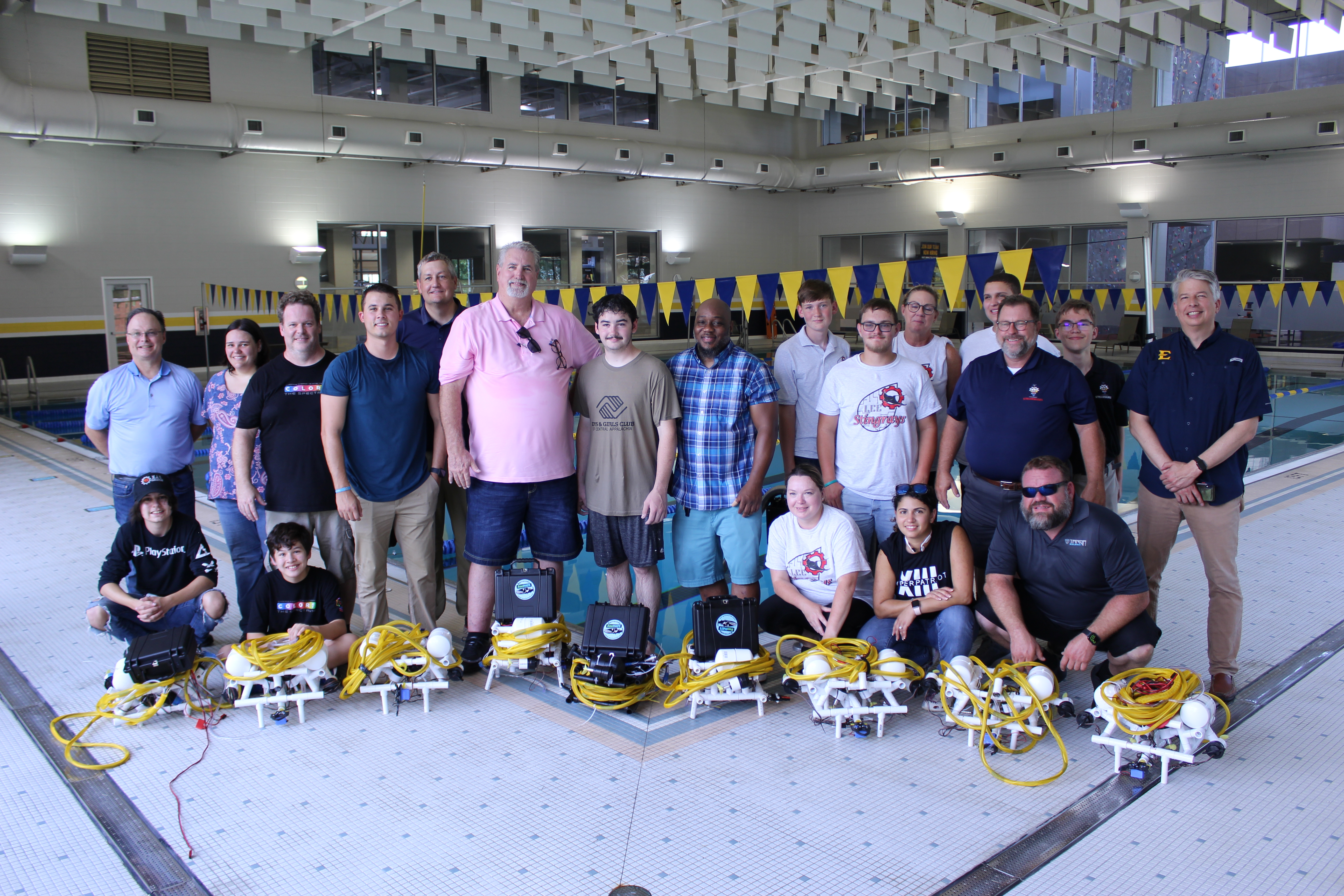 Group of about 20 people pose with underwater robots at the ETSU swimming pool.