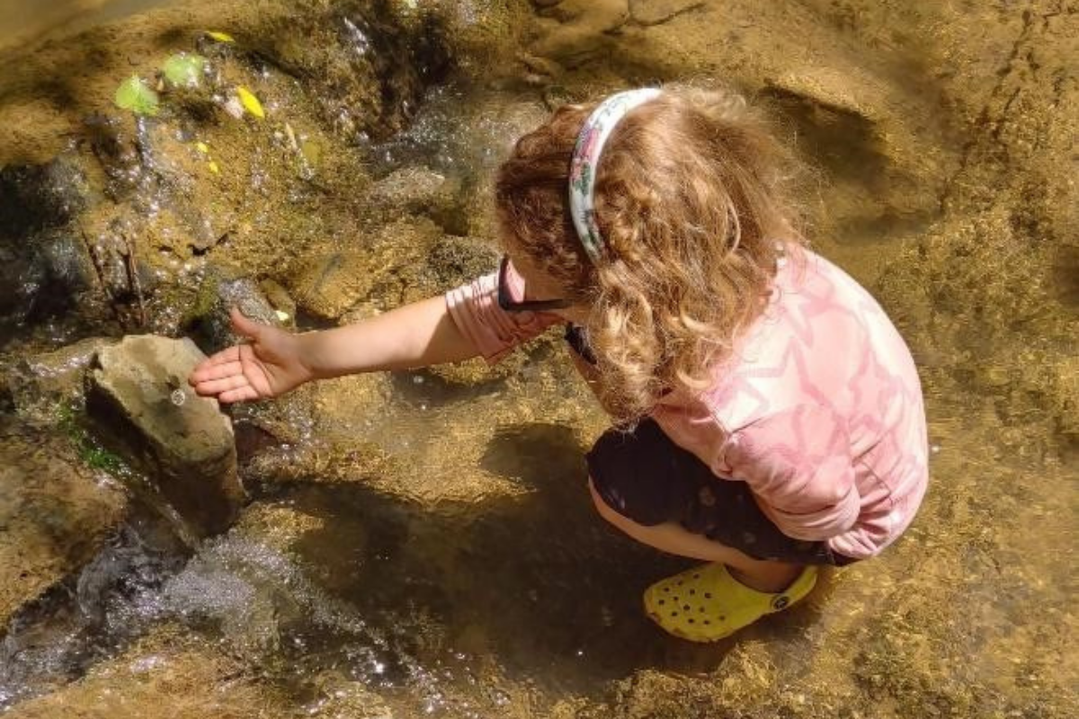 A child playing in river water from the creek bed. 